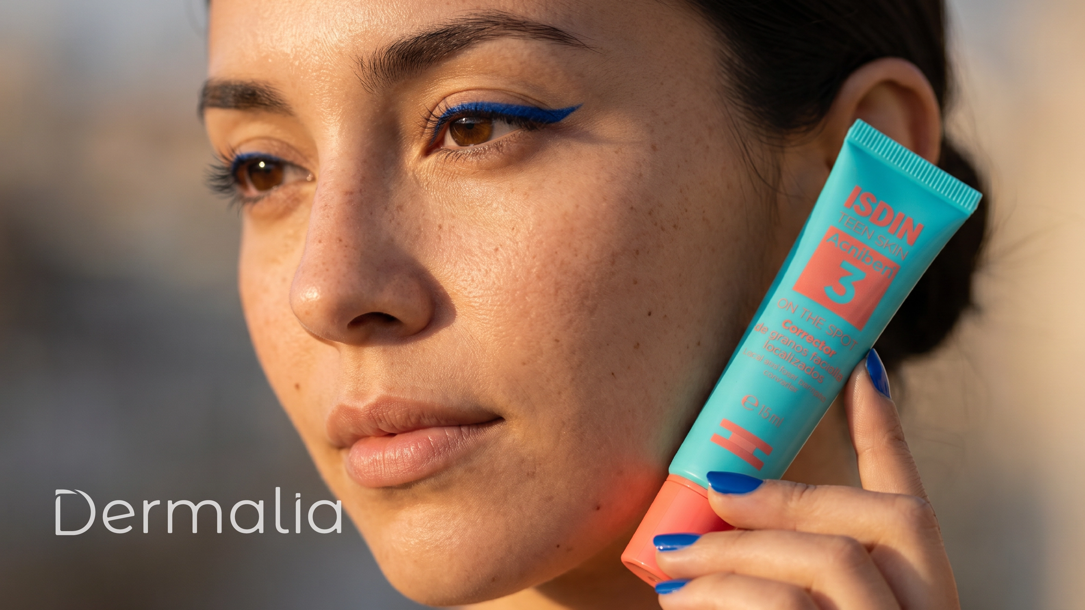 Mujer sosteniendo Acniben On The Spot Corrector de Granos Gel de ISDIN junto al rostro para el cuidado de la piel con tendencia acneica.