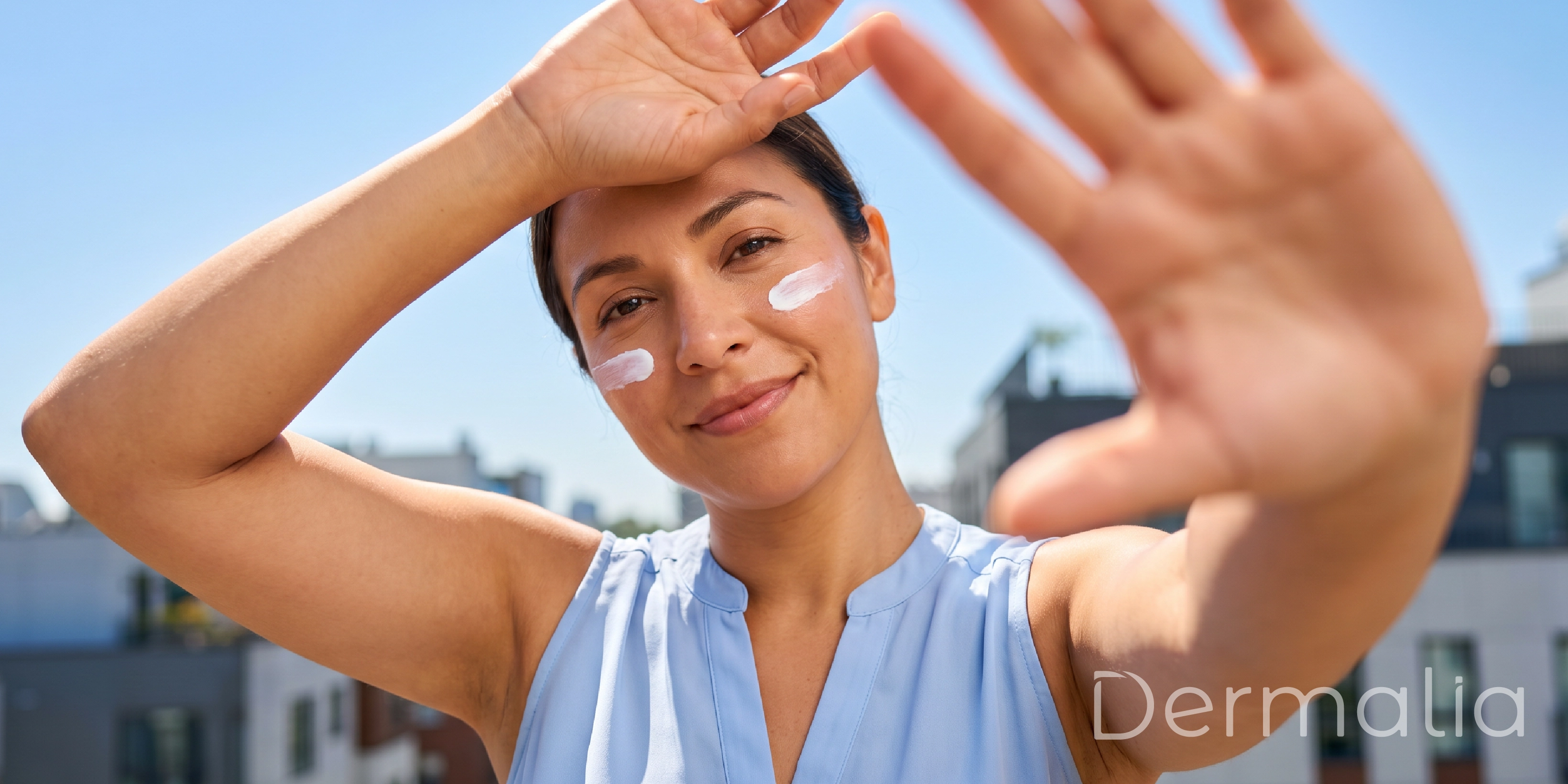 Mujer aplicando protector solar facial al aire libre para proteger la piel de los rayos UV durante el día.