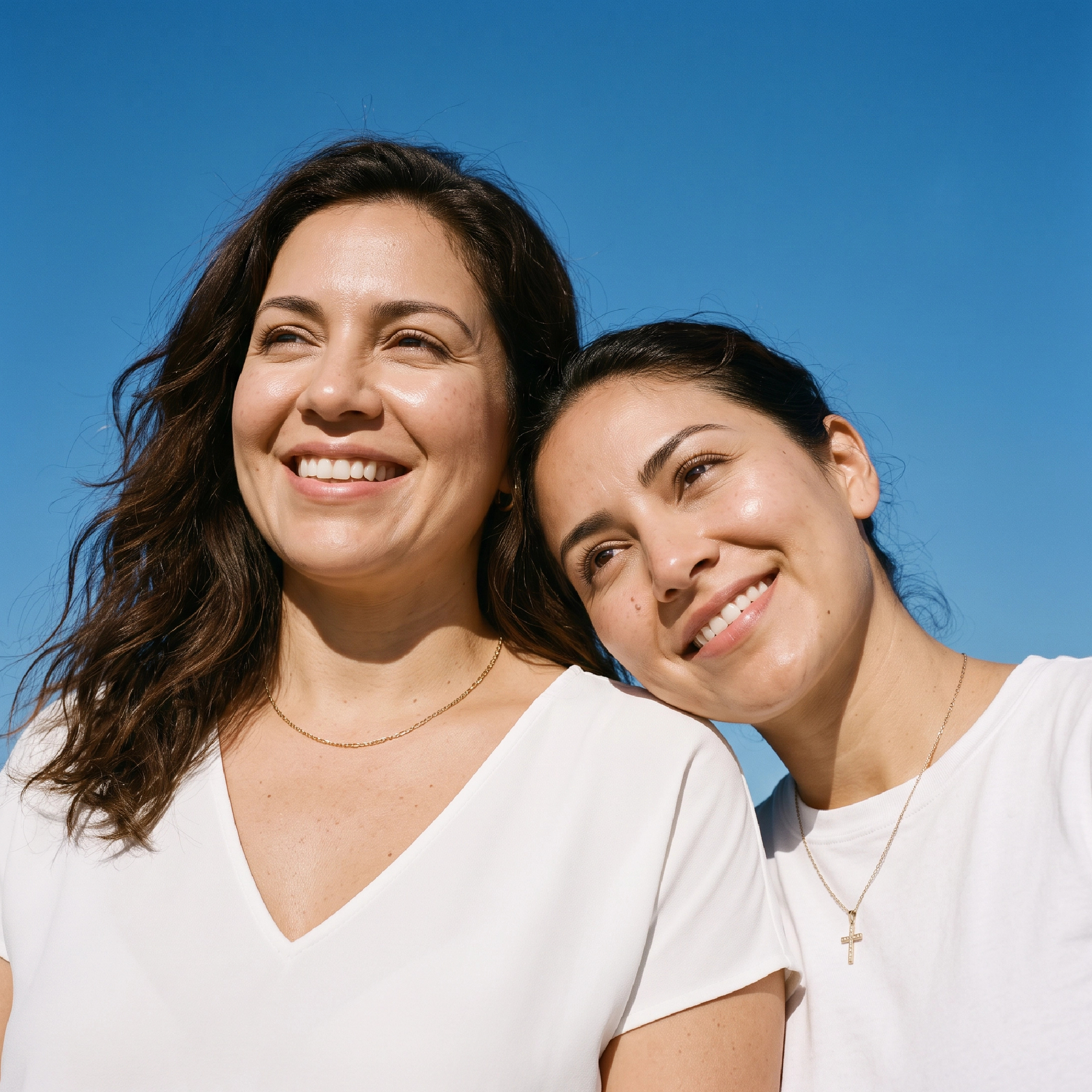 Mujeres sonriendo al aire libre con piel de aspecto saludable.