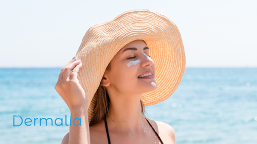 Mujer aplicando protector solar en el rostro frente al mar.