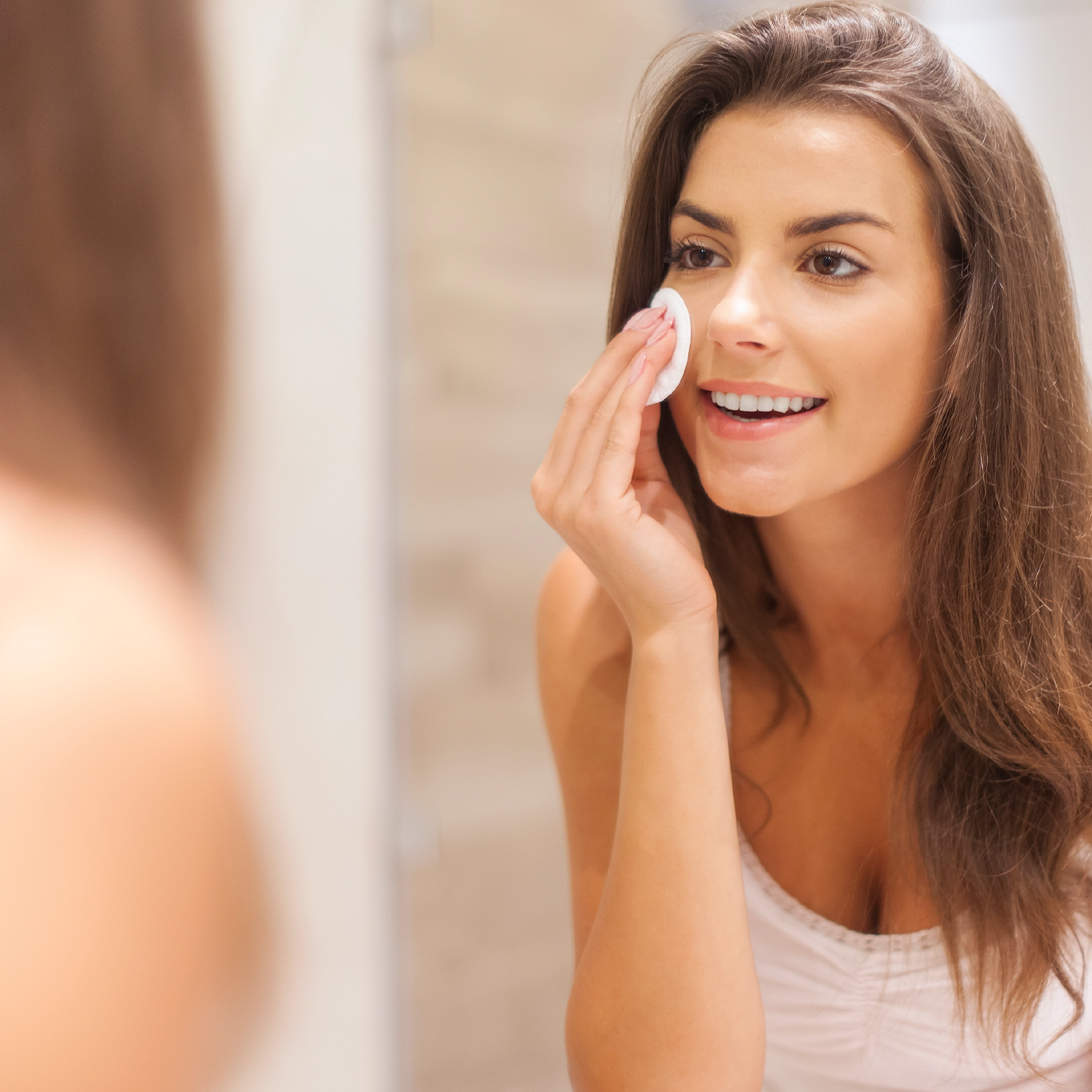 Mujer limpiando su rostro con un algodón durante su rutina de skincare antes de aplicar productos para el cuidado de la piel.