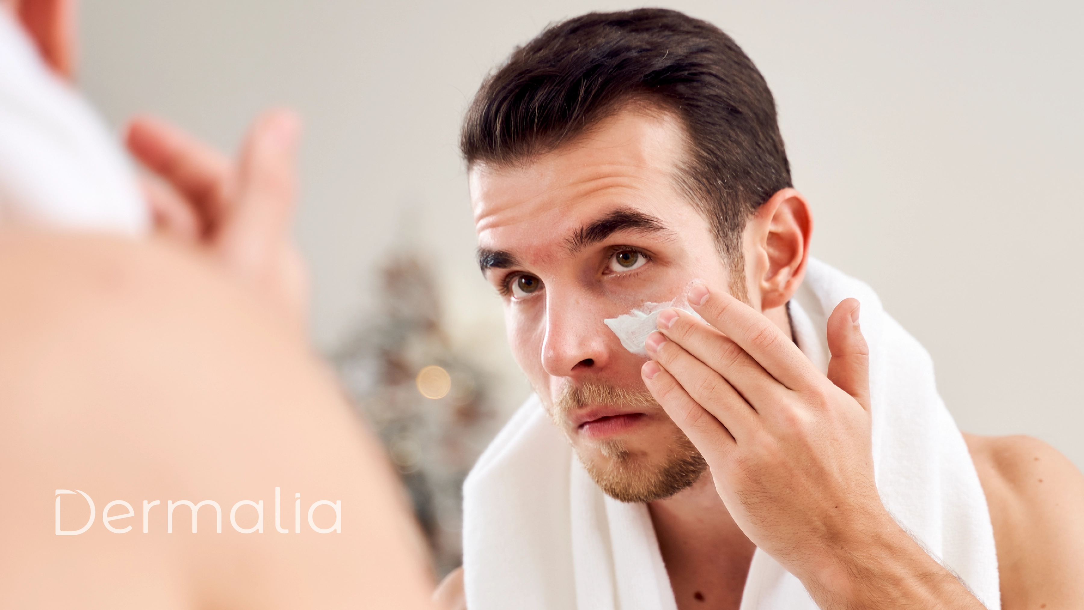 Hombre aplicando crema facial frente al espejo durante su rutina de skincare para favorecer la hidratación y el cuidado diario de la piel.